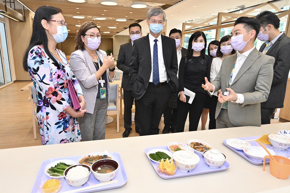 關懷備至:  安老院營辦機構文化村的代表向羅致光（前排左三）介紹方便長者吞嚥的營養軟餐。
