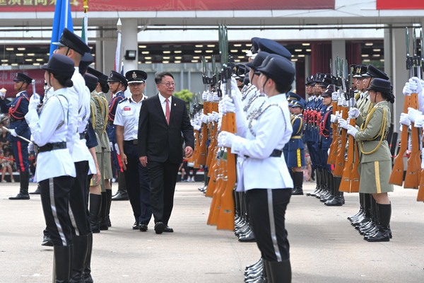 團結一致: 陳國基（左二）檢閱紀律部隊儀仗隊和青少年制服團體。