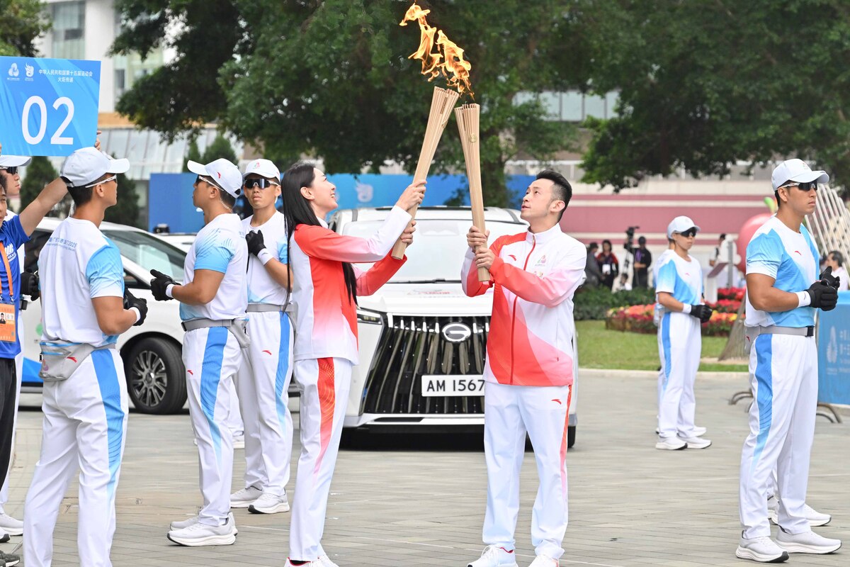 火炬傳遞:  黃鎮廷（右）把火種傳給第二棒火炬手孫一文。