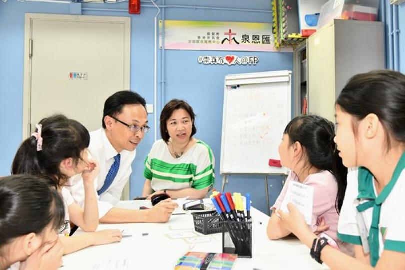 童心傾聽: 聶德權（左三）到訪水泉澳邨的綜合服務中心，參觀興趣班上課情況，並與學童交談。