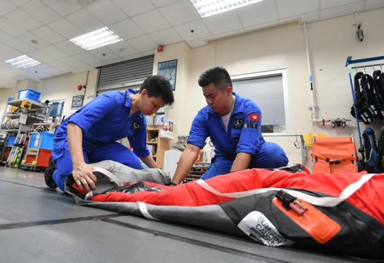 合作無間: 陳穎琳（左）擔任飛機技術員，與男同事合作檢查救生設備。