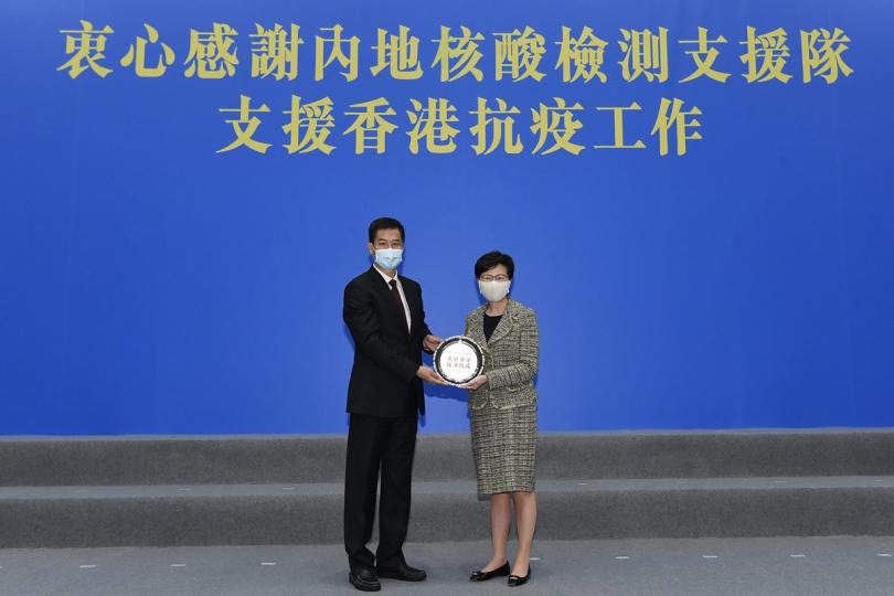感謝支援:  林鄭月娥（右）向內地核酸檢測支援隊總領隊李大川頒授紀念銀碟。