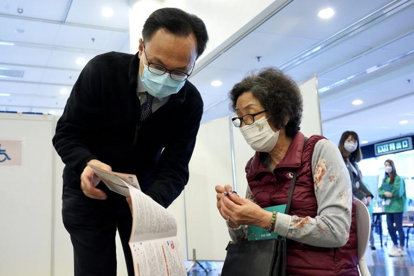 關懷長者: 60歲或以上人士屬於優先接種組別,聶德權(左)在社區疫苗接種中心與長者交談。 關懷長者: 60歲或以上人士屬於優先接種組別,聶德權(左)在社區疫苗接種中心與長者交談。