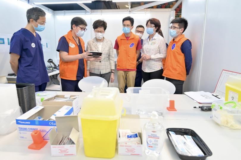 了解運作: 林鄭月娥(左三)聽取營運社區疫苗接種中心的醫療機構人員介紹中心運作情況。 了解運作: 林鄭月娥(左三)聽取營運社區疫苗接種中心的醫療機構人員介紹中心運作情況。