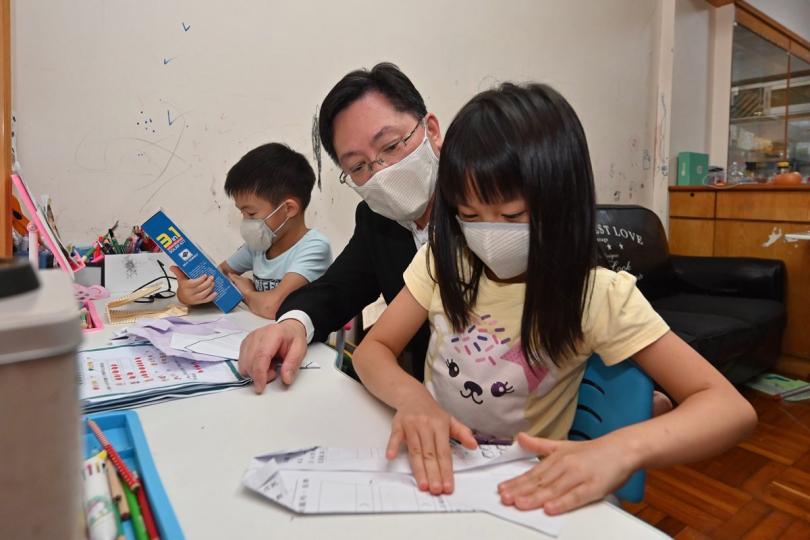 關心基層:  薛永恒（中）參與香港科創義工聯盟「慶回歸 賀百年」社區送暖活動，探訪觀塘區內一戶分租房戶，了解一對龍鳳胎的學習情況。