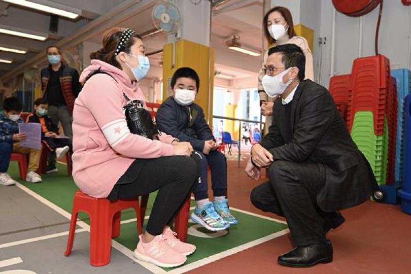 走進校園:  楊潤雄（右）與家長和學生交談，了解外展接種服務情況。