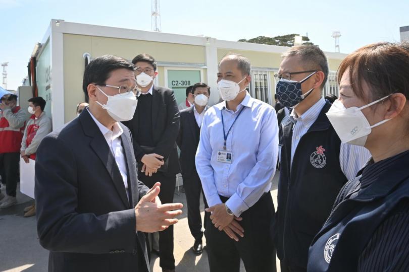 打氣:  李家超（左一）視察中央援建位於青衣的社區隔離設施，與在場的民眾安全服務隊工作人員交談。