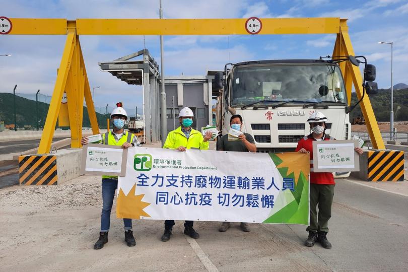 齊心抗疫:  環保署人員在新界東南堆填區向建築廢物收集車司機派發快速抗原測試套裝。