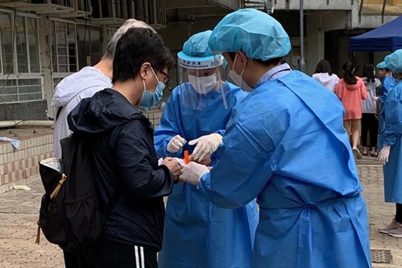 妥為受檢:  工作人員在屯門蝴蝶邨蝶意樓為檢測結果呈陰性的居民佩戴手環，證明他們已接受強制檢測。