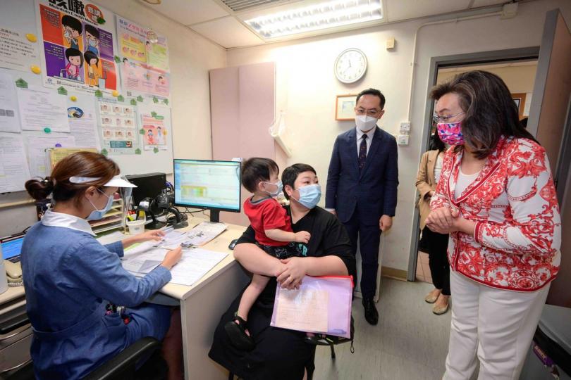 及早保護: 楊何蓓茵(右)到西九龍母嬰健康院,了解健康院為幼童提供新冠疫苗接種服務的安排,並向一名17個月大男童的家長介紹有關服務。 及早保護: 楊何蓓茵(右)到西九龍母嬰健康院,了解健康院為幼童提供新冠疫苗接種服務的安排,並向一名17個月大男童的家長介紹有關服務。