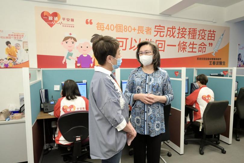 推而廣之:  楊何蓓茵（右）聽取長者安居協會行政總裁王虹虹介紹熱線中心如何透過接觸一線通平安鐘服務使用者，鼓勵長者接種新冠疫苗。
