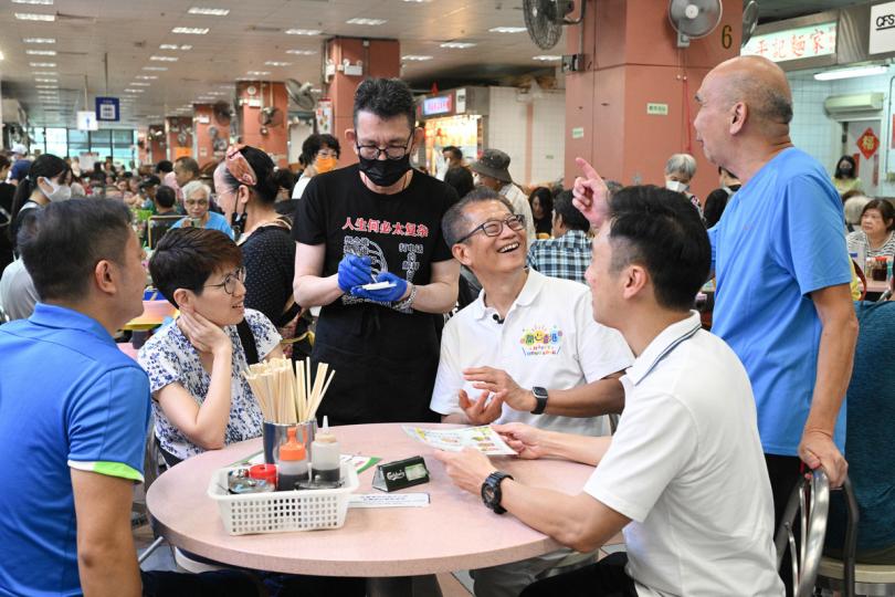 愉快傾談: 第二期消費券7月16日發放,陳茂波(右三)將剛收到的消費券用作加碼消費,並到地區與市民閒話家常。 愉快傾談: 第二期消費券7月16日發放,陳茂波(右三)將剛收到的消費券用作加碼消費,並到地區與市民閒話家常。