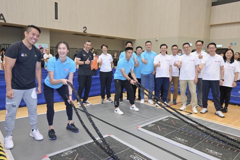 運動同樂:  李家超（右六）觀看游泳運動員譚凱琳（左二）和武術運動員劉紫康（左五）體驗電子戰繩。
