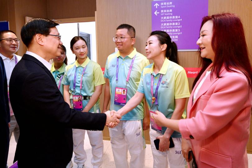 服務他人:  李家超（左）與杭州亞運會志願者交流。