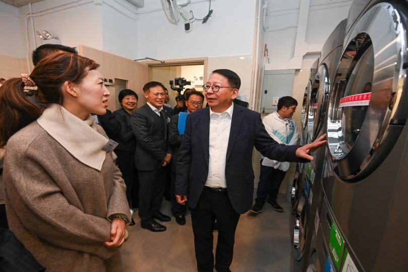 改善生活:  陳國基（前排右一）參觀深水埗社區客廳內的自助洗衣站。