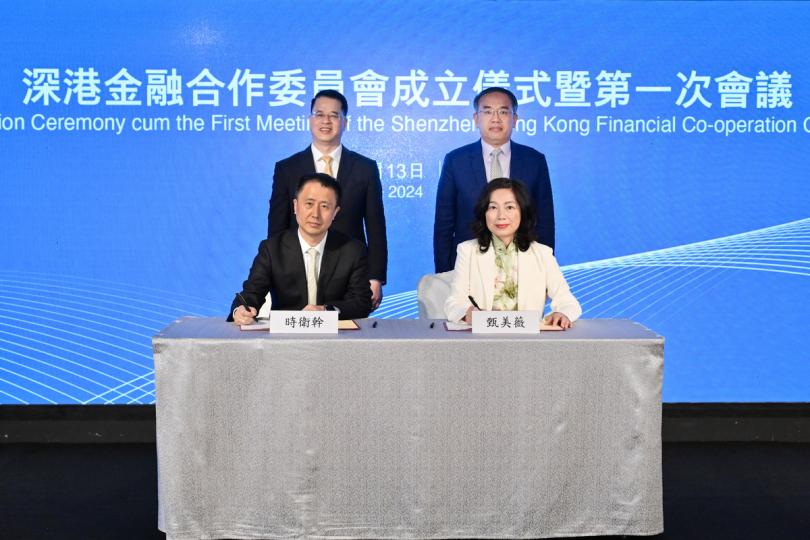 深港協作:  許正宇（後排右）與羅晃浩（後排左）見證財庫局和深圳市地方金融管理局代表簽署合作意向書。