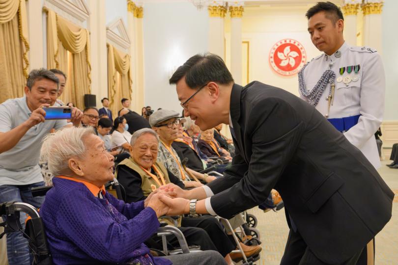心懷家國:  李家超（右二）向老戰士頒發由國家授予的紀念章。