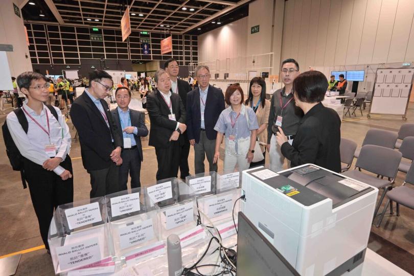 有序高效:  陸啟康（右五）巡視設於會議展覽中心的選委會界別分組補選中央點票站，視察工作人員實地演練，確保點票工作順利進行。