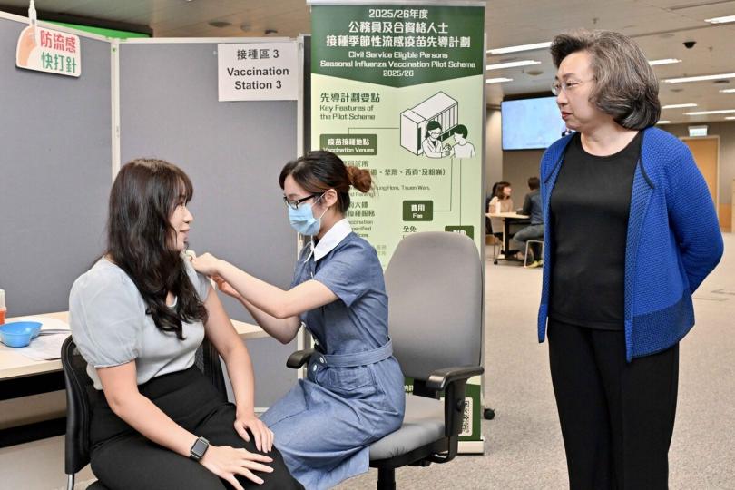 保障健康:  楊何蓓茵(右)在外展站與接種流感疫苗的公務員交談。 保障健康:  楊何蓓茵(右)在外展站與接種流感疫苗的公務員交談。