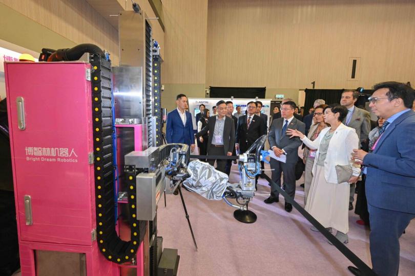 創新不斷:  何永賢（右二）在「共築．智能峰會」參觀會場內的機械人展示區，並和與會人士互動交流。