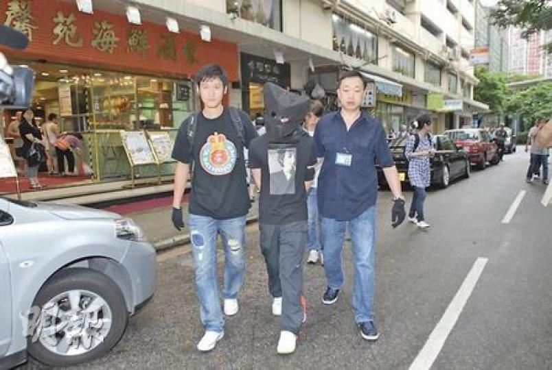 警方在柴灣拘捕15歲「個體戶小毒梟」，將他以黑布蒙頭帶署扣查。（劉友光攝）