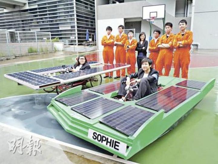 由青衣IVE學生設計的兩款太陽能車SOPHIE，是全港首輛全太陽能發電汽車，由15名男生及1名女生組成製作隊伍。參與研發的陸清慧（後排中）說，雖然太陽能汽車仍在研發階段，但期望可突破電動車技術，加強使用再生能源。圖右綠色的是SOPHIE第一代，圖左為第二代，兩車成本分別為4萬及8萬元。（彭美芳攝）