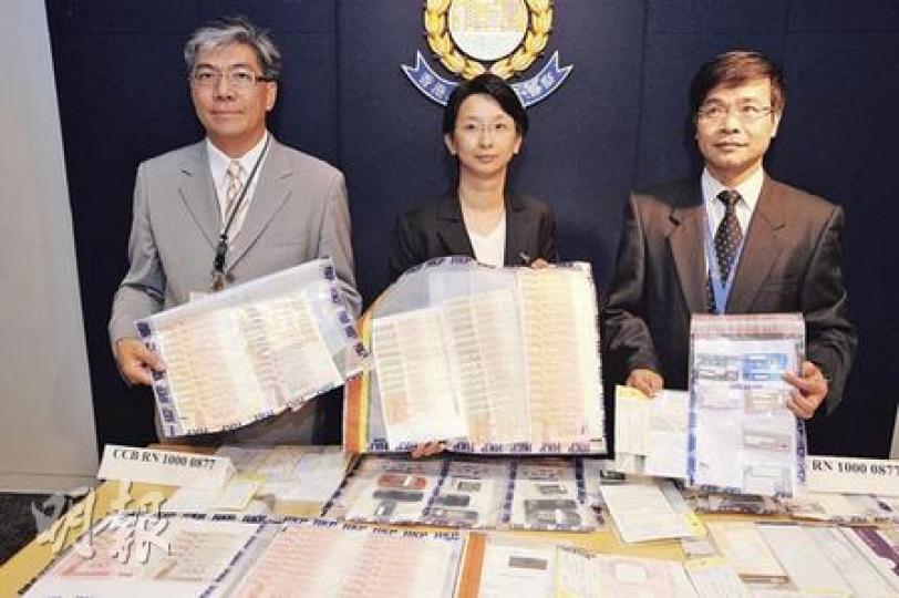 商業罪案調查科警司陳綺麗（中）展示跨國行騙集團案中檢獲的大量現金及銀行提款卡等證物，她說，騙徒靠打電話及發電郵「白撞」騙財。（樊銳昌攝）
