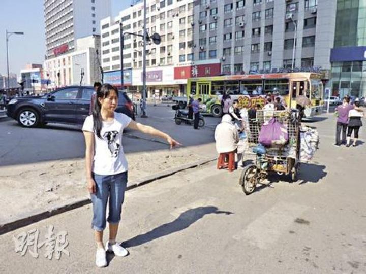 張晶指認當天丈夫被打的地點，現時仍有不少小販擺賣。（明報記者攝）