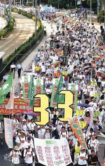 昨日七一遊行，主辦單位民陣稱遊行人數達5.2萬人，是2003年以來的第三低數字。今年遊行除了爭取普選、廢除功能組別，還關注勞工權益，有遊行人士高舉「33」字樣，寓意爭取最低工資時薪33元。（林振東攝）
