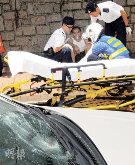 黃翁在禧福道被消防私家車撞傷後被扶到路邊救治，遇事車輛擋風玻璃龜裂及遺下一束傷者的頭髮。（蘇偉明攝）