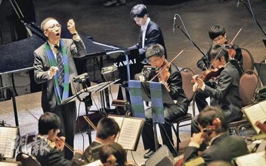 華仁校慶音樂會上，食物及衛生局副局長梁卓偉（左一）手執指揮棒，帶領師弟們演奏《黃河協奏曲》，獲得全場掌聲回報。（余俊亮攝）賽馬會主席陳祖澤（右），昨晚在母校華仁的校慶音樂會上再使出拿手好戲《禪院鐘聲》。（余俊亮攝）