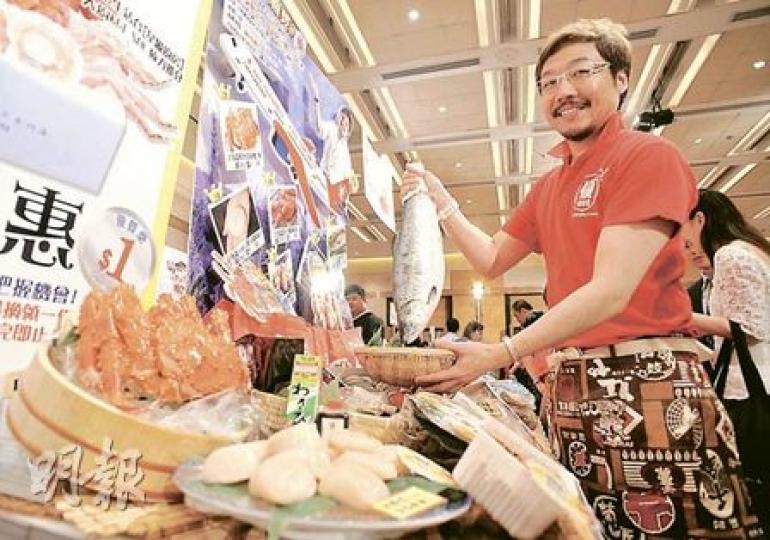 優質堂「煮持人」杉內馨拿起大魚，向記者展示博覽會吸引顧客的招數「1元大優惠」。（葉漢華攝）