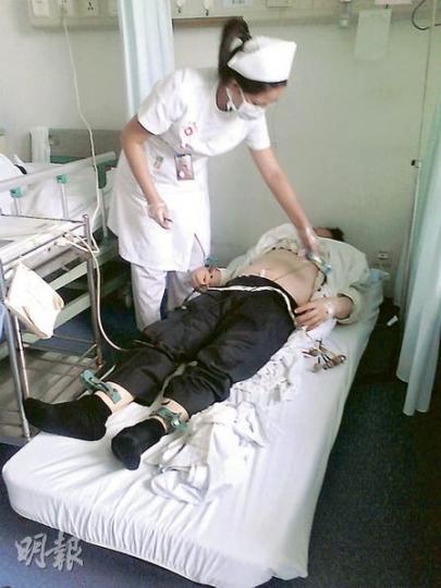 深圳南山醫院護士正替杜振峰做心電圖及檢查，前晚已送院的杜仍穿著恤衫西褲，得知有香港記者找他時，以被鋪蒙頭。（明報記者攝）