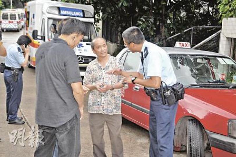 的士司機（中）幸保不失，在場向警員講述遇劫經過，他眼部曾被匪徒用噴霧射中，需送院檢驗。（胡永輝攝）協助擒匪的晨運客（持傘者）向警員講述匪徒掙脫逃去的經過。（胡永輝攝）