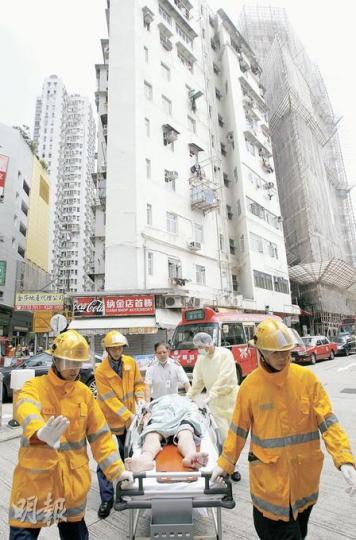 墮樓男子一直昏迷，廣華醫院急症室護士聯同消防員合力在救護車到場前，先用滑輪病牀將事主送院。（林振東攝）患有思覺失調的男子在廣華街墮樓重傷，廣華醫院急症室人員（白衣）搶先到現場，聯同消防員拯救傷者。（林振東攝）