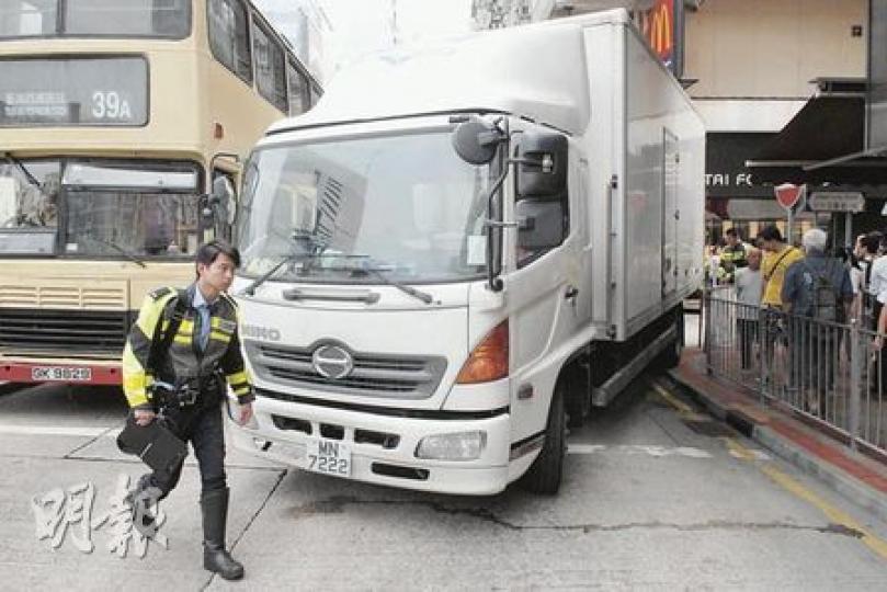 密斗貨車轉入沙嘴道時，左尾轆貼近行人路石壆，把一名站於鐵欄外等候過路的婦人夾困在車身與鐵欄之間。（蘇偉明攝）