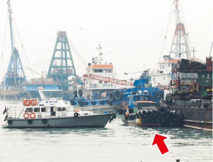 肇事駁艇（箭嘴示）事後停泊在油麻地避風塘一艘躉船旁，海事處船隻（左）駛近駁艇調查。（劉友光攝）