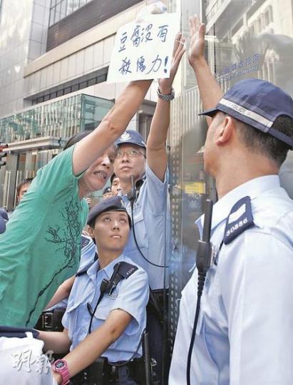 一批社運人士昨在警察總部外抗議，「女長毛」雷玉蓮（綠衣者）昨示威時高舉一袋豆腐，諷刺「豆腐沒有殺傷力」。（李紹昌攝）