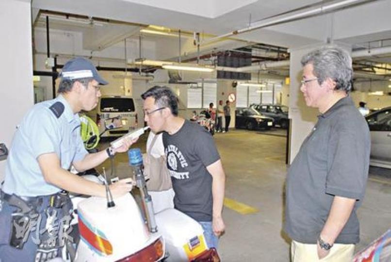 肇事私家車司機（中）在律師（右）陪同下接受酒精呼氣測試，證實未有酒後駕駛。（劉友光攝）
