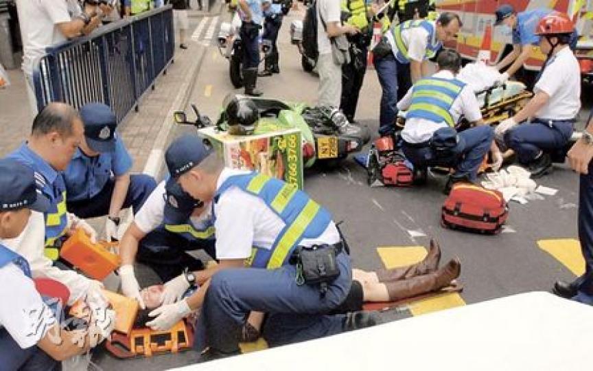 兩名被電單車撞及女途人倒卧馬路中，救護員到場即時兩人包紮再送院。（劉友光攝）