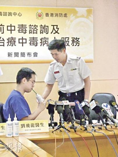 醫管局中毒諮詢中心副顧問醫生陳志強（左）示範，病人須坐着自行飲用50克「萬能解毒劑」。（林景輝攝）