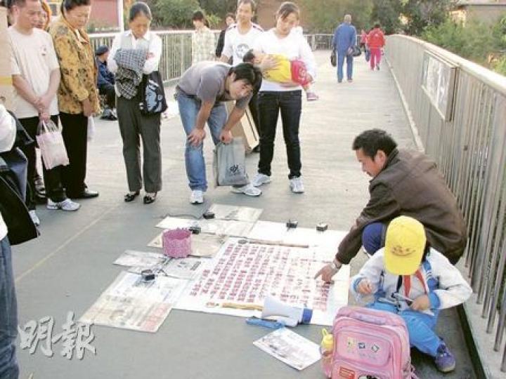 在無工打時,覃父就上街乞討,曉艷在一旁做功課,吸引不少路人關注的目光。(明報記者攝)每當假期,曉艷就到工廠剪線頭。(明報記者攝) 在無工打時,覃父就上街乞討,曉艷在一旁做功課,吸引不少路人關注的目光。(明報記者攝)每當假期,曉艷就到工廠剪線頭。(明報記者攝)