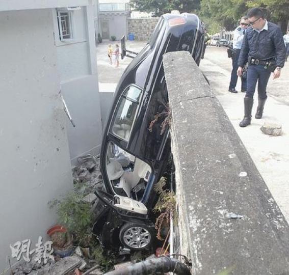 前日才在運輸署登記、車價逾300萬元的賓利房車，落地不足一天，昨早便在飛鵝山撞穿圍牆，飛墜直插一間別墅後門地面，車頭盡毁。（劉友光攝）拖車公司到場把失事賓利房車吊回地面，有外籍住客走出拍照留念。（梁琬珊攝）