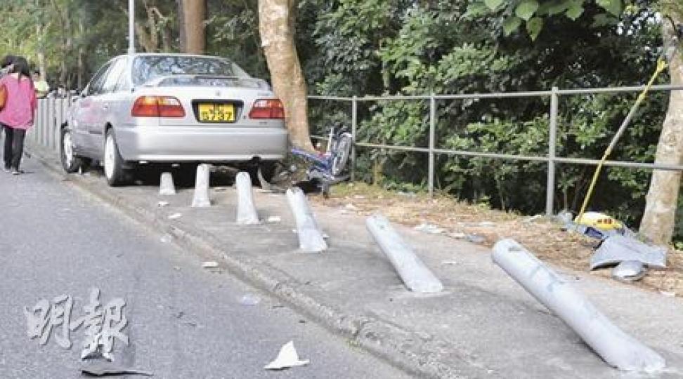 西沙路一輛私家車越線剷上對面行人路，掃毁8條防撞鐵柱後停下，其間更將一輛單車撞至斷成兩截，擱在一旁。（林錫禮攝）