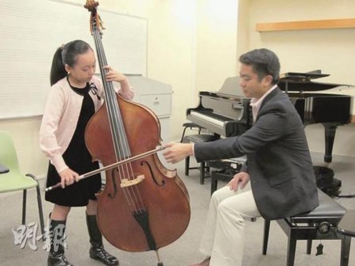 9歲女生麥晞靖（左）剛贏得柏林低音大提琴9至10歲組別冠軍，演藝學院老師鄭景聰（右）說，平日斯文的晞靖，一到比賽便施展渾身解數，充滿音樂感。（彭美芳攝）