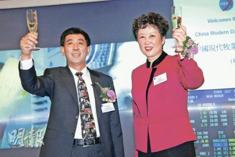 現代牧業在港首日上市，董事長鄧九強（左）和總裁高麗娜（右）舉杯慶祝之時，其身後的熒幕顯示屏，一開市便顯示其股票跌穿招股價。（陳智良攝）