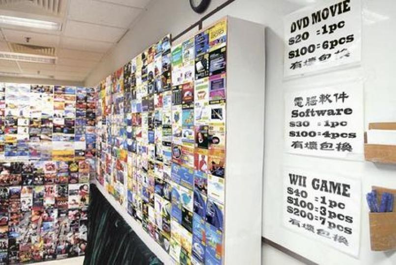 翻版光碟販子以減價吸引顧客,電影DVD每隻賣20元,買6隻收100元,有壞包換,客人隨時可用紙筆(圖右)落單購買。(何朝財攝) 翻版光碟販子以減價吸引顧客,電影DVD每隻賣20元,買6隻收100元,有壞包換,客人隨時可用紙筆(圖右)落單購買。(何朝財攝)