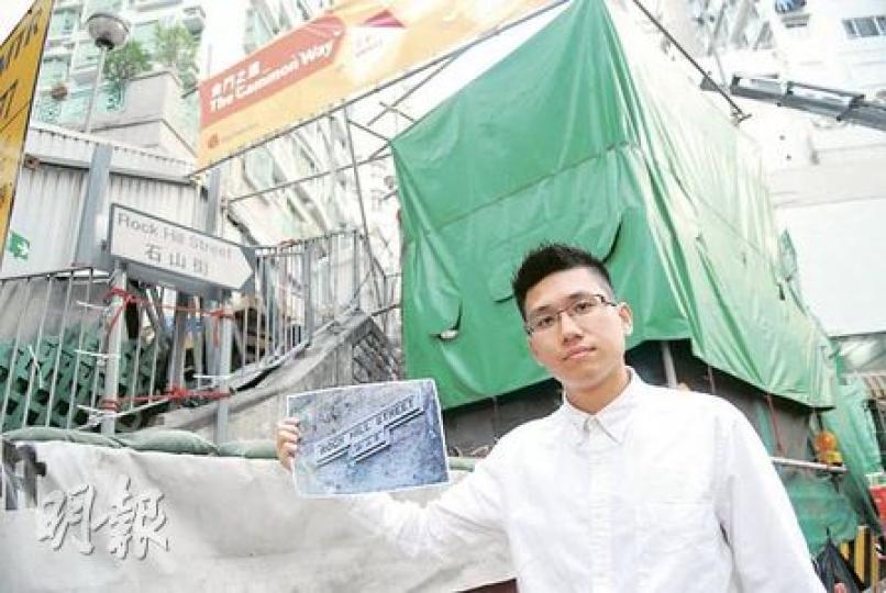 「80後」中學教師吳文俊，過去5年遍尋殖民地年代遺下的T形舊街牌，近日發現西環石山街依附斜坡上的石製街牌（他手上相片展示原貌），被港鐵西港島線地盤帆布遮蓋，擔心街牌被拆掉，去信多個政府部門要求保育。運輸署回覆本報表示，會原地保留該石製街牌。（陳淑安攝）
