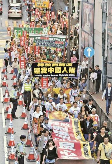 昨日遊行隊伍兩旁警方幾乎「五步一哨」，亦有便衣探員沿路跟隨。 （葉漢華攝）中聯辦宣傳文體部部長郝鐵川昨日留守大樓，更不時探頭觀看示威情况。（陳雪玲攝）劉先生：「劉曉波為中國民主獻出力量，國家仍然囚禁他，無疑暴露出中共政權在國際舞台上的失敗，我不想坐在家中什麼都不去做，所以出來遊行。」（陳雪玲攝）楊先生：「警察好明顯成為國家機器，一見遊行去中聯辦就如臨大敵，與舊時開放社會截然不同……自由如此倒退，我真的對香港政府很失望！」（陳雪玲攝）