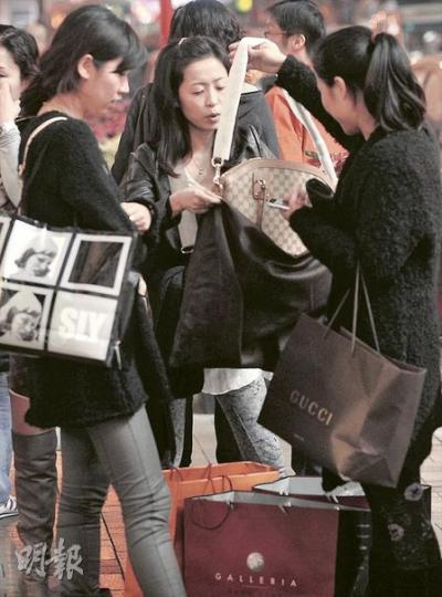 中國海關規定國民只能帶價值5000元以內的物品過境,否則就會被徵稅,內地遊客遂各出其謀避稅,有人買相機時先試拍幾張相片假扮自用,有人則索性即時打開名牌手袋,隨身攜帶,當作自用。(余俊亮攝)(明報製圖) 中國海關規定國民只能帶價值5000元以內的物品過境,否則就會被徵稅,內地遊客遂各出其謀避稅,有人買相機時先試拍幾張相片假扮自用,有人則索性即時打開名牌手袋,隨身攜帶,當作自用。(余俊亮攝)(明報製圖)